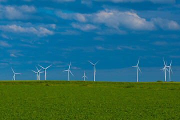 Windmills set in a green field against a blue sky.Wind generator in green grass.renewable energy.Alternative energy sources.Environmentally friendly natural energy source.Natural energy. 