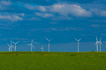 Windmills set in a green field against a blue sky.Wind generator in green grass.renewable energy.Alternative energy sources.Environmentally friendly natural energy source.Natural energy. 