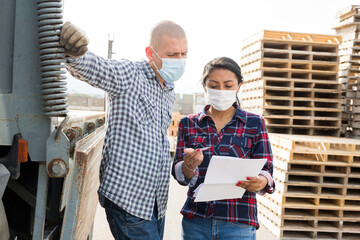 Woman manager protective mask giving instructions to a worker at the construction site of a...
