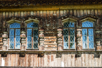 facade of an old wooden building. Windows with curly bars. Walls with the corrosion of time.