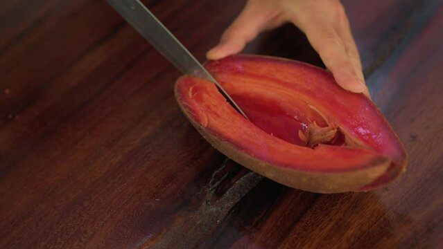 Close up shot of woman hand cutting exotic fruit zapote.