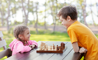 the older brother is teaching the younger sister to play chess