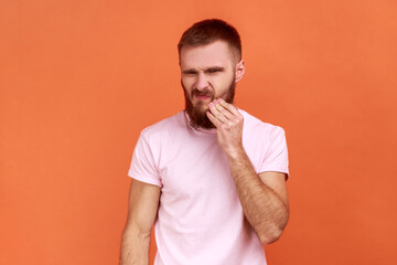 Dental problem. Portrait of bearded man touching his cheek and grimacing from terrible toothache,...