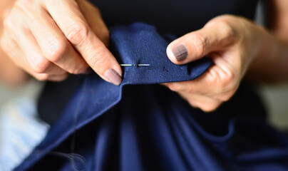 Women's hands are doing sewing activities with traditional craftsmanship.