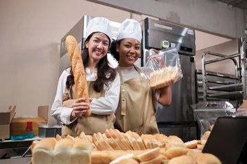 Tuinposter Portrait of professional chefs in apron uniforms with hats looking at camera with cheerful smile and proud with bread in kitchen. Friend and partner of bakery foods and fresh daily bakery occupation. © tigercat_lpg