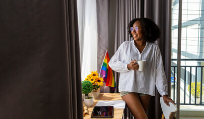 African American girl with LGBTQ rainbow flag in her bed room for coming out of the closet and...