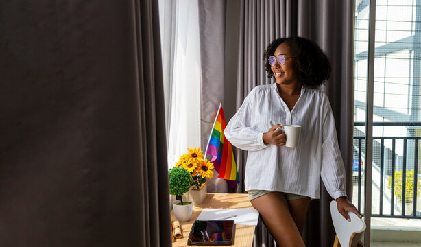 African American girl with LGBTQ rainbow flag in her bed room for coming out of the closet and pride month celebration to promote sexual diversity and equality in homosexual orientation concept