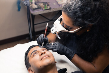 Obraz na płótnie Canvas application of micro pigmentation technique on a man's eyebrows