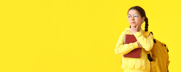 Cute little schoolgirl on yellow background with space for text