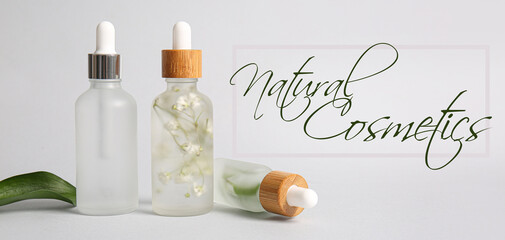 Fototapeta na wymiar Bottles of essential oils and text NATURAL COSMETICS on light background