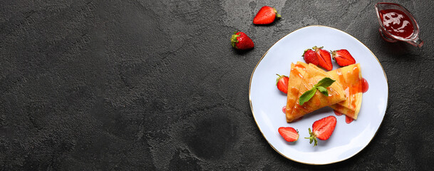Plate of thin pancakes with strawberry and jam on dark background with space for text