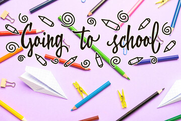 Text GOING TO SCHOOL and set of stationery on color background