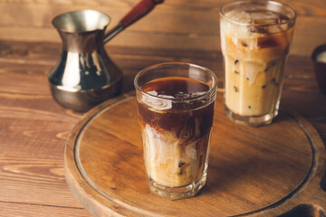 Glasses of cold brew coffee with milk on wooden board