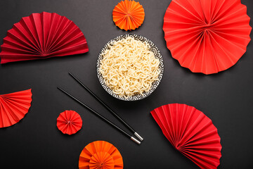 Composition with tasty noodles in bowl and chopsticks on black background