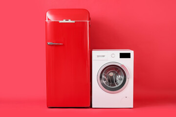 Stylish retro fridge and washing machine on red background