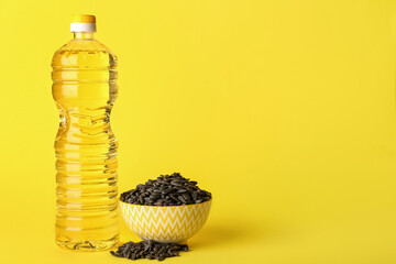 Fototapeta na wymiar Bottle of oil and bowl with sunflower seeds on yellow background