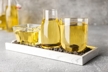 Board with oil and sunflower seeds on grunge background, closeup