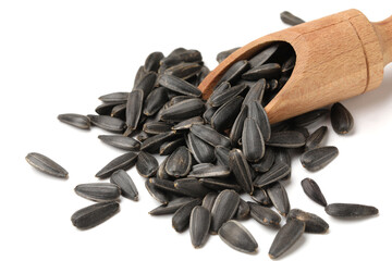 Wooden scoop and unpeeled sunflower seeds on white background, closeup