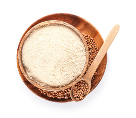 Plate with bowl of flour, spoon and buckwheat grains on white background
