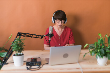 Middle-aged female radio presenter talking into the microphone and reading news - radio broadcast...