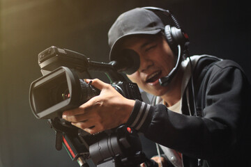 Fototapeta na wymiar Cameraman with a camera on a tripod at studio