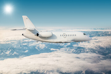 Fototapeta na wymiar White modern luxury corporate aircraft flies over snow-covered mountain ranges