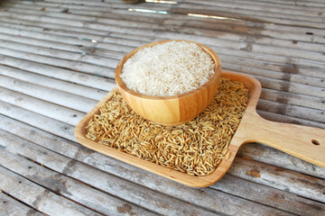 White rice (Thai Jasmine rice) on wooden bowl and wooden plate Put on a bamboo table.