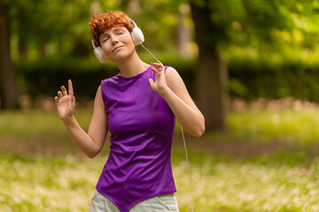 Androgynous woman in headphones dancing in park