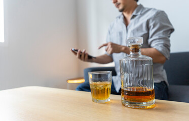 Man enjoy a glass of whiskey sitting at sofa at home.