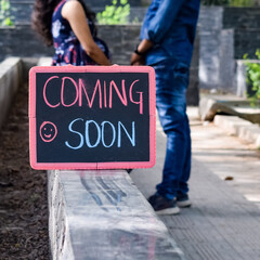 Indian couple posing for maternity baby shoot. The couple is posing in a lawn with green grass and the woman is falunting her baby bump in Lodhi Garden in New Delhi, India