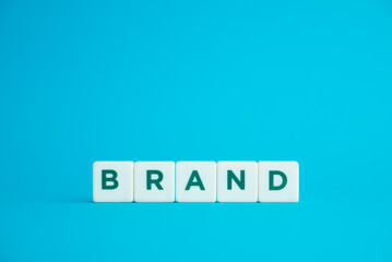 BRAND identity building and digital marketing strategy concept. Word BRAND alphabets word on blue background with copy space.