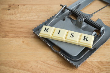 Word RISK in a rat trap on wooden table background copy space. Risk management, risk assessment in...