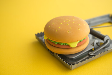 Hamburger fast food in a rat trap on yellow background copy space. Junk foods, unhealthy, people office lifestyle concept. Junk foods are full high calories, fat and excess sodium that bad for health. - obrazy, fototapety, plakaty