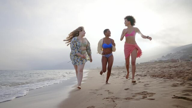 Beautiful multiethnic young women having fun on the beach during the summetime vacation. Storytelling representation of body positivity, self acceptance and individuality female concepts