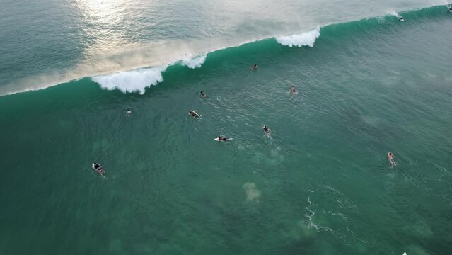 Close-out wave break quickly and surfers can not ride it, aerial shot of surf zone near Dreamland beach at evening time. People learn surfing, enjoy water sports, South Kuta shore of Bali island