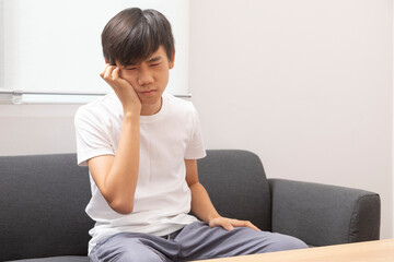 Asian teen boy wearing t-shirt. suffer from tooth pain. Dental problem - teenager suffering from toothache.