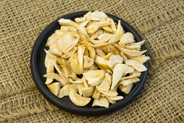 Dried garlic flakes on black plate close up flat lay photo on grey textured wooden background