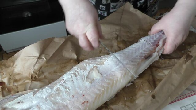 chef cleans cod fish with a knife