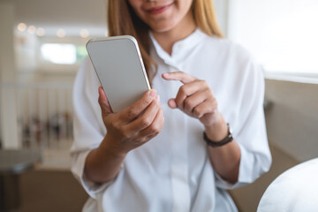 Closeup image of a young woman holding and using mobile phone