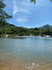 Tranquil natural scene with blue mountains, blue sky, and scattered rocks on the rippling river. Eco-tourism on a sunny day