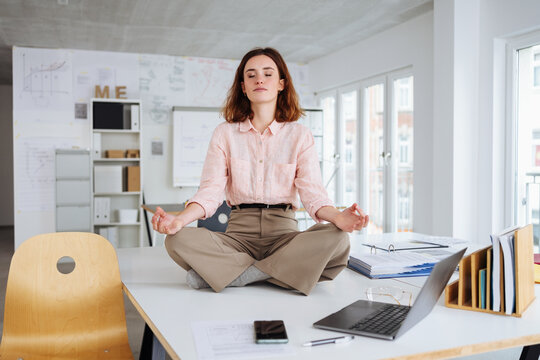 business woman does yoga on desk in office and relaxes