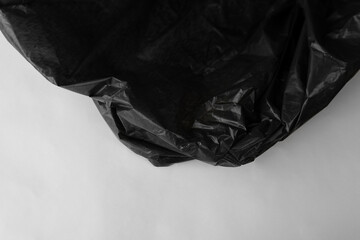 Closeup crumpled single use or non recyclable shiny black dark color plastic trash bag made from polyethylene texture white hygiene isolated background. Environment care concept
