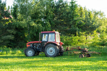 Red tractor standing by the trees after hard works.