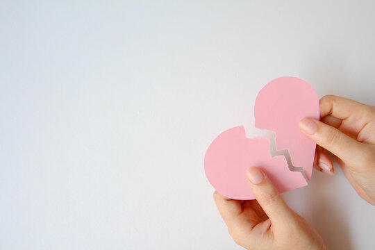 hand holding pink paper broken heart on white background. - Powered by Adobe