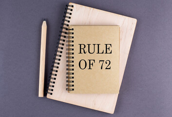 Word RULE OF 72 on notebook with pencil on the grey background