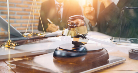 Obraz premium Justice and law concept.Male judge in a courtroom with the gavel, working with, computer and docking keyboard, eyeglasses, on table in morning light