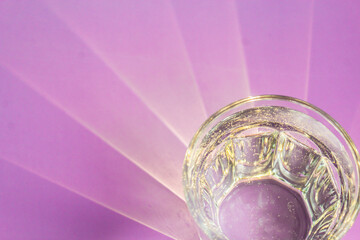 Bizarre patterns from the sun on a lilac table. The sun's rays pass through a glass faceted glass of water