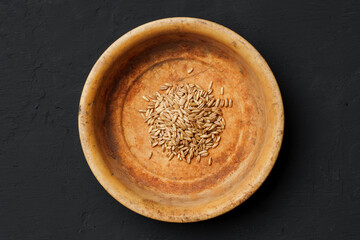 Concept of a global food crisis caused by hunger due to lack of grain. Plate with small amount of grain on plate on black background