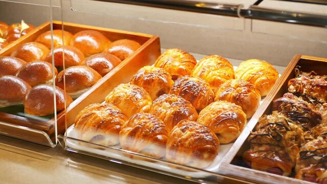 Assorted pastry and bread arranged on tray selling at bakery shop.