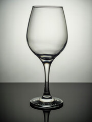 An empty wine glass stands on a grey surface